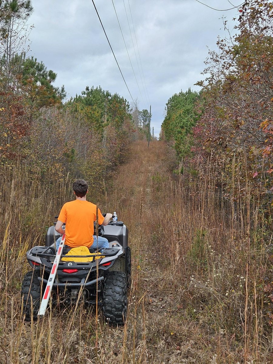 J2 fielder riding an ATV down a cleared right-of-way